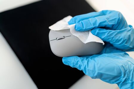 Office sanitizing wipe wiping mouse and mousepad with disinfecting wipes. Coronavirus COVID-19 sanitize cleaning disinfection of work desk. Antibacterial wipe the surfaces against corona virus.の写真素材