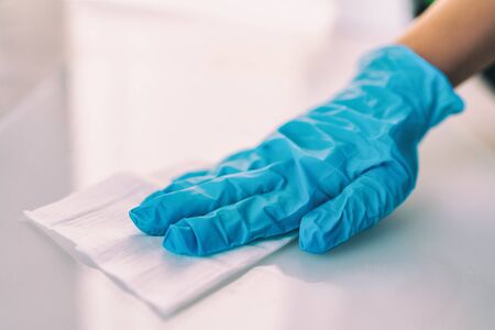 Surface disinfecting home cleaning with sanitizing antibacterial wipes protection against COVID-19 spreading wearing medical blue gloves. Sanitize surfaces prevention in hospitals and public spaces.の写真素材