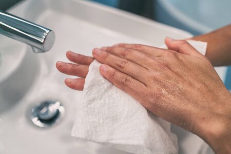 Washing hands steps for personal hygiene COVID-19 prevention drying hand with paper towel after handwash. Coronavirus infection preventive cleaning.の写真素材