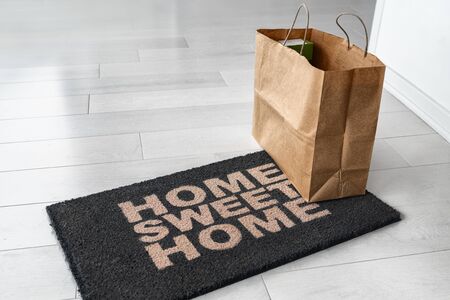 Home delivery of food grocery bag left at door entrance mat for Corona virus prevention safety....