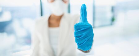 Coronavirus success happy news lab researcher doing thumbs up with medical gloves for vaccine. PPE for COVID-19 healthcare banner panoramic.の写真素材