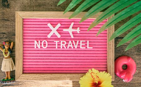 Coronavirus travelling ban sign. Travel cancelled due to COVID-19. NOT TRAVEL text written in pink felt letter board with tropical background for summer vacation.の写真素材