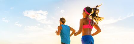 Runners fitness couple running together on sunset sky background panoramic banner. HIIT workout athletes people doing cardio exercise.Active lifestyle.の写真素材