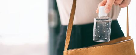 Hand sanitizer travel bottle woman carrying in purse COVID-19 prevention alcohol gel for cleaning hands while outside doing errands. Coronavirus virus pandemic banner panoramic header.の写真素材
