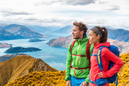 Hiking couple wanderlust adventure and travel concept with hikers relaxing looking at view. Hiking couple tramping up famous hike to Roys Peak on South Island, New Zealand.の写真素材