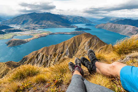 Wanderlust adventure and hiking travel vacation concept with hikers hiking boots close up. Hiker couple tramping up famous hike to Roys Peak on South Island, New Zealand. Couple resting and relaxing.の写真素材