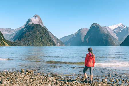 New Zealand - tourist couple hiking looking at Milford Sound enjoying iconic view and famous tourist destination in Fiordland National Park, South Island, New Zealand.の写真素材