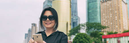 Phone Asian mature woman traveling using mobile 5g device on business trip travel city lifestyle...