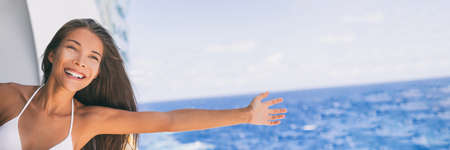Cruise ship vacation travel fun freedom woman. Asian tourist girl on holidays feeling free with open arms towards ocean water on Caribbean getaway holiday.の写真素材