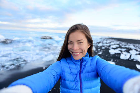 Adventure selfie by trave explorer woman on Iceland Diamond Beach. Woman tourist in amazing landscape Ice beach, Breidamerkursandur by jokulsarlon glacial lagoon / glacier lake nature.の写真素材