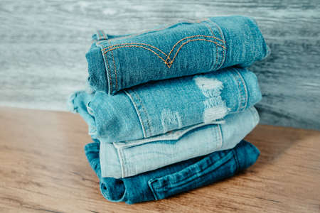 Jeans pants on display shelf at retail clothing store - many blue shades of denim pile of clothes on...