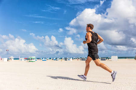 Fit man running jogging exercising on South Beach, Miami, Florida on beach. Runner athlete working...