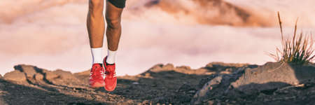 Running shoes of runner training endurance on trail run outdoors in mountains background. Panoramic banner.の写真素材