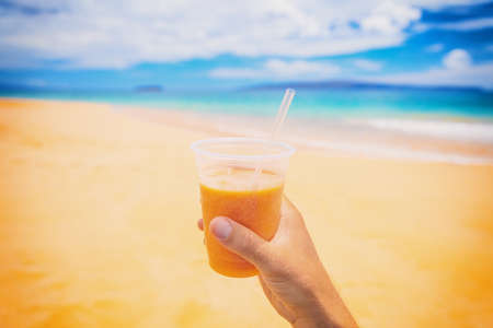 Healthy juice smoothie juice drink selfie on beach. Turmeric, carrot, papaya or orange fruit, Man...