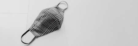 Cloth face mask for corona virus protection in plaid fabric houndstooh pattern on white background panoramic header. Fashion textile masks for autumn fall clothing outfit banner .の写真素材