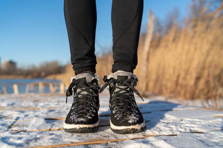 Winter boots woman walking on ice and snow in nature park