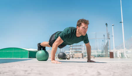 Fit exercises man strength training core doing balance push-ups workout at outdoor gym balancing on...