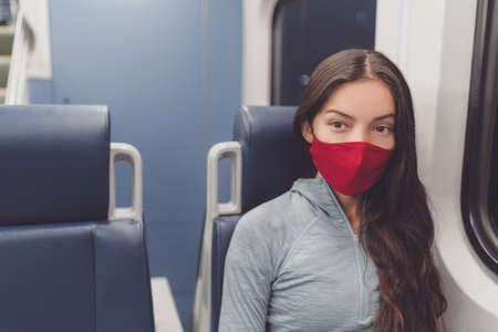 Woman wearing face mask in public transportation during coronavirus pandemic. Face mask wearing on train transport commuter. Multiracial woman passenger using cloth mouth covering on commute.の写真素材