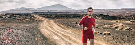 Trail running athlete man runner on mountain path in compression clothes wearing tech device smartwatch wearable watch for cardio tracking. Fitness outdoors.の写真素材