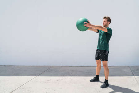 Medicine ball workout fitness man strength training arms doing deltoid front raise exercise for...
