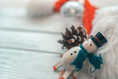 Christmas white background with miniature snowman wood toy, pine cone, ball ornament and santa hat for xmas festivities.の写真素材
