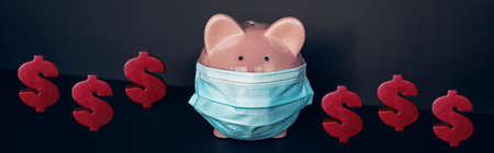 Money saving during pandemic concept. Piggy bank wearing face mask with red dollars bills banner panoramic background.の写真素材