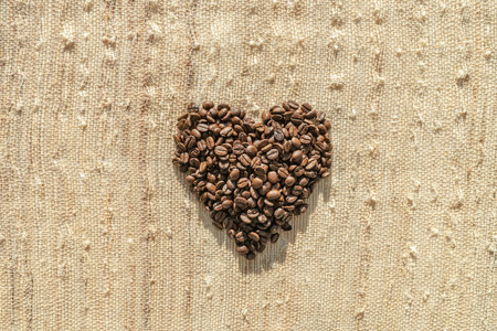 Coffee beans top flat view of heart shaped cafe background coffee lover concept on rustic bag textureの写真素材