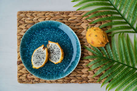 Yellow pitaya dragonfruit sliced presented on blue plate on table. Organic dragon fruit fresh and...