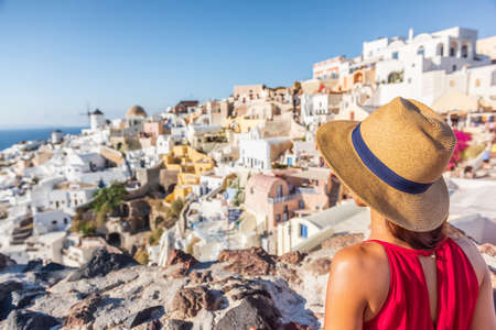 Travel vacation greece santorini woman tourist looking at Oia village view, luxury Europe destination holiday. Summer vacationsの写真素材