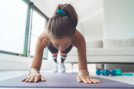 Plank exercise at home. Woman doing online fitness class body core workout on yoga mat