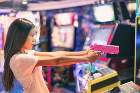 Arcade game machine adult woman shooting gun video games playing light shoot videogame virtual realityの写真素材