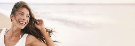 Happy young Asian woman natural beauty banner. Beautiful girl laughing smiling with perfect teeth looking to the side in happiness header panoramic. Biracial multiethnic modelの写真素材