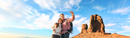 Selfie tourists taking photo with mobile phone at summit of mountain hike panoramic. Nature trek couple hikers hiking with backpacks in Europe panoramic banner.の写真素材