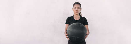 Woman athlete cross training carrying throwing heavy medicine ball doing squats and ball slam.の写真素材