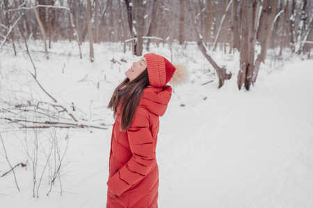 Winter outdoor happy relaxing Asian woman breathing fresh cold winter air serene and zen doing wellness walk walking outside in forest nature for mental healthの写真素材