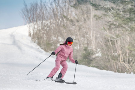 Skiing - Woman on ski. Alpine ski concept - skier skiing downhill at mountain snow covered ski trail slopes in winter on perfect powder snow enjoying nature landscape. Elegant pink ski clothingの写真素材