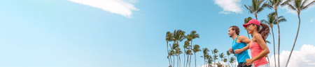 Athlete sport runners couple running landscape banner. Fitness people couple jogging together in summer park outdoor. Horizontal palm trees background. Asian girl, Caucasian friend manの写真素材
