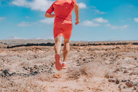 Running shoes back view of professional runner athlete ultra running man wearing red compression shorts for outdoor summer trail run training sprinting in tough terrain on desert landscapeの写真素材