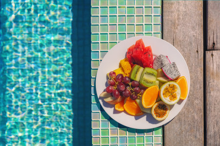 Vacation food fruit plate breakfast top view by the hotel swimming pool background. Luxury resort...