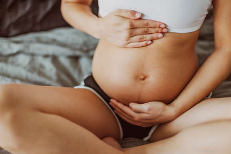 Pregnancy belly stretch marks and linea nigra. Pregnant woman caressing holding stomach during first...