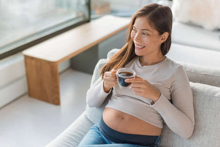 Asian pregnant woman drinking coffee cup at home. Pregnancy foods and drinks to avoid