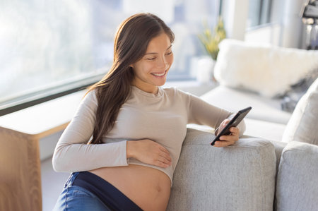 Pregnant Asian woman happy using mobile phone app for shopping or telemedicine. Pregnancy lifestyle...