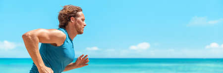 Runner man athlete running on blue ocean and sky banner landscape . Sport active fitness lifestyle panoramic background. Beach run guy profile portraitの写真素材