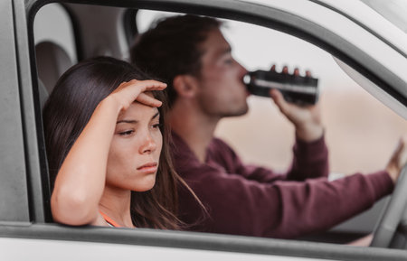Drunk driving couple upset tired from drinking in car. Man driver holding beer beverage at the...