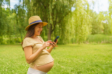 Pregnant woman using phone app reading about pregnancy or shopping baby things online. Portrait of...