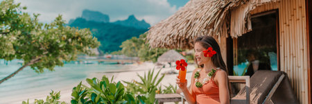 Woman drinking tropical fruits juice morning breakfast at hotel room balcony on beach. Vacation travel in Bora Bora, French Polynesia landscape banner panoramic. Happy tourist enjoying summer holidayの写真素材