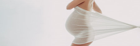 Pregnant woman maternity artistic photoshoot. Pregnancy profile portrait showing beautiful big belly baby bump in third trimester. Woman expecting baby shot in profile in panoranmic banner imageの写真素材