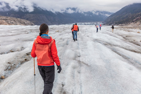 Alaska glacier hiker woman on cruise ship excursion. tourist girl walking with group of hikers on blue ice adventure nature vacation, popular activity in Alaska holidaysの写真素材
