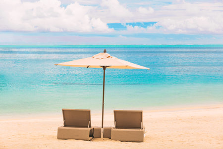 Beach luxury resort tropical vacation Caribbean destination. Two loungers chairs with sun umbrella on blue ocean sea water paradise getaway backgroun.dの写真素材