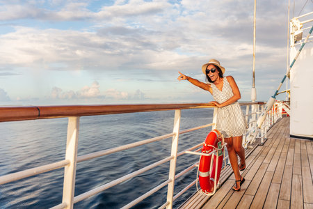 Happy cruise vacation fun travel woman pointing watching whales or wildlife sighting from deck of boat on Europe summer destination cruising vacation holiday. Luxury relaxation getaway.の写真素材